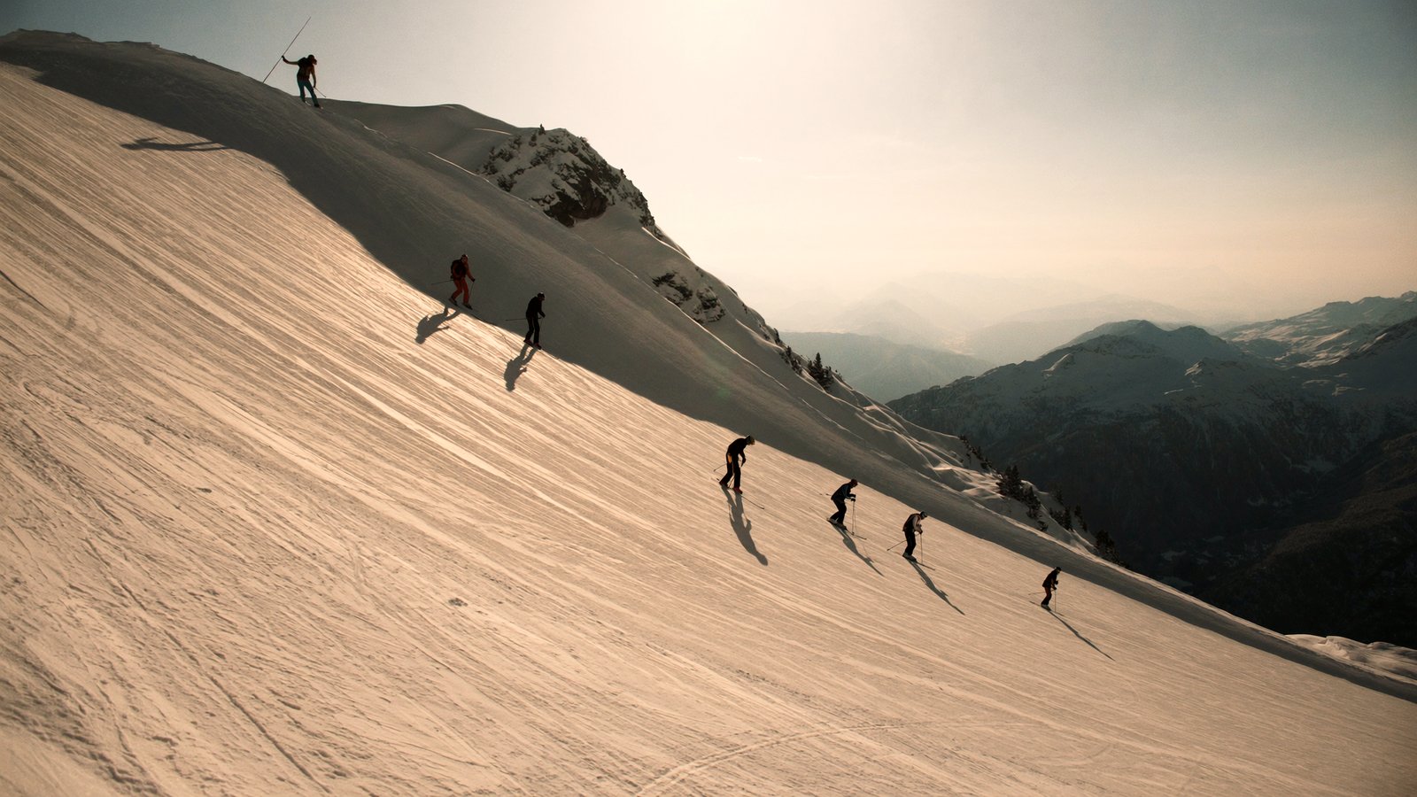 Skiers on a wide groomed piste above Courchevel