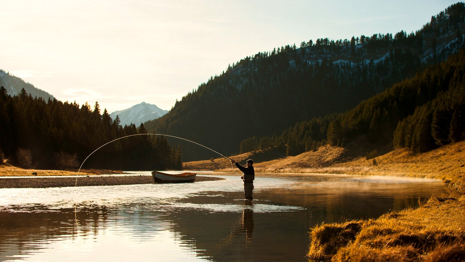 A fly fisherman casting on a clear mountain river at golden hour in the Rockies
