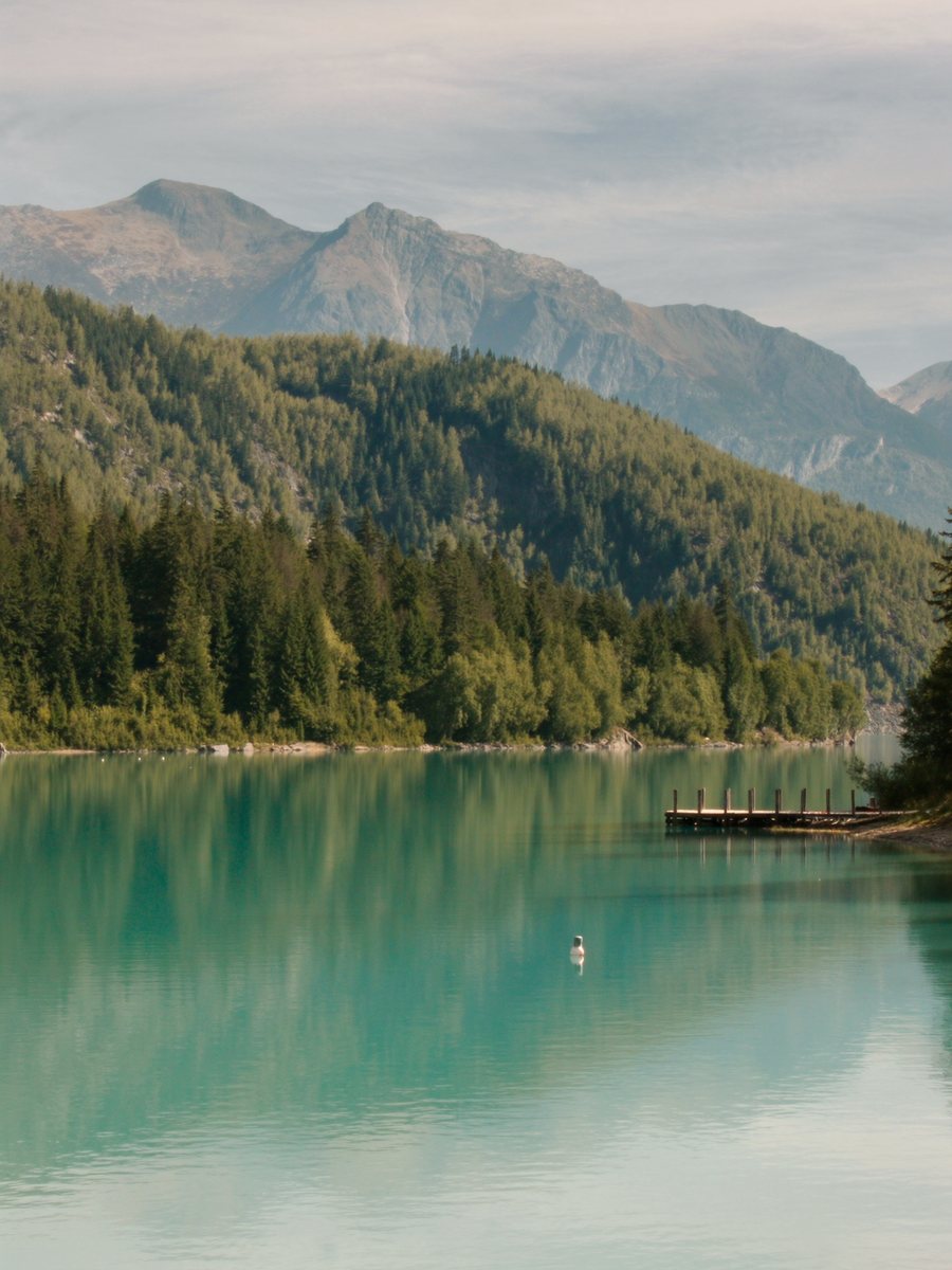 A turquoise alpine lake below Whistler&rsquo;s green summer mountains